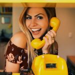 woman holding yellow rotary telephone